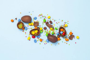 Kırık ve bütün çikolata Paskalya yumurtaları, mavi arka plan üzerinde renkli tatlılar. Paskalya, Paskalya süsleri, Paskalya tavşanı tatlılar için arama kutluyor kavramı. Düz yatıyordu, en iyi görünüm. Kopya alanı