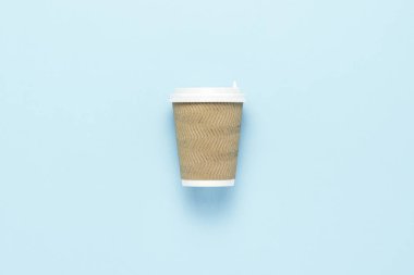 Tek kullanımlık kağıt bardak sıcak kahve veya çay üzerinde mavi bir arka plan için plastik bir kapak ile. Düz yatıyordu, en iyi görünümü