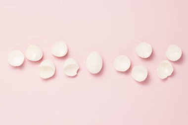 Beyaz yumurta ve pembe bir arka plan üzerinde etrafında kırık yumurta. Hayat sigortası, sağlık ve özelliği, bir çocuğun doğumu için bekleyen kavramı. Düz yatıyordu, en iyi görünümü