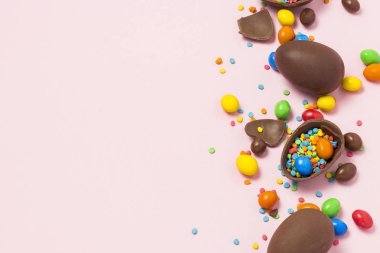 Kırık ve bütün çikolata Paskalya yumurtaları, çok renkli tatlılar, pembe bir arka plan. Çalı. Paskalya, Paskalya süsleri kutluyor kavramı. Düz yatıyordu, en iyi görünüm. Uzay kopyalayın. Mutlu Paskalya