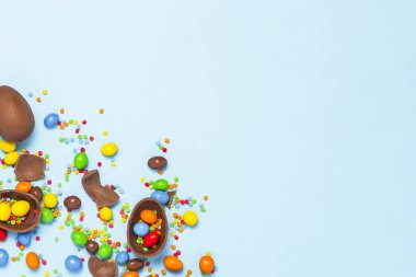 Kırık ve bütün çikolata Paskalya yumurtaları, mavi arka plan üzerinde renkli tatlılar. Paskalya, Paskalya süsleri, Paskalya tavşanı tatlılar için arama kutluyor kavramı. Düz yatıyordu, en iyi görünüm. Kopya alanı