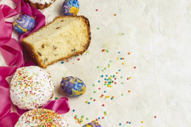 Paskalya kek ve tek parça, pembe kurdele, hafif bir arka plan üzerinde renkli tatlılar. Ortodoks Paskalya kavramı.