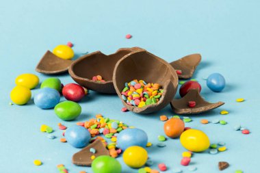 Kırık çikolata Paskalya yumurtası ve mavi bir arka plan üzerinde renkli tatlılar. Paskalya kutlamaları kavramı