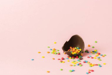 Kırık çikolata Paskalya yumurtası ve pembe bir arka plan üzerinde çok renkli tatlılar. Paskalya kutlamaları kavramı