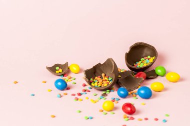 Kırık çikolata Paskalya yumurtası ve pembe bir arka plan üzerinde çok renkli tatlılar. Paskalya kutlamaları kavramı