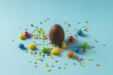 Çikolata Paskalya yumurtası ve mavi bir arka plan üzerinde çok renkli tatlılar. Paskalya kutlamaları kavramı