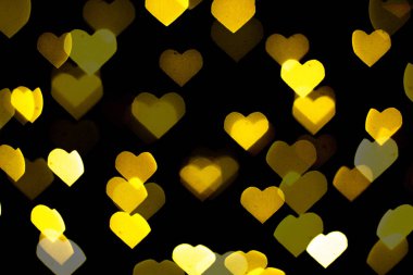 Siyah arka planda güzel sarı ve beyaz bir bokeh. Arkaplan ya da duvar kağıdı olarak kullanılabilir. Kalp şeklinde. Aşk Konsepti, Sevgililer Günü