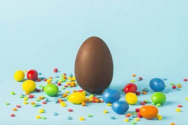 Çikolata Paskalya yumurtası ve mavi bir arka plan üzerinde çok renkli tatlılar. Paskalya kutlamaları kavramı