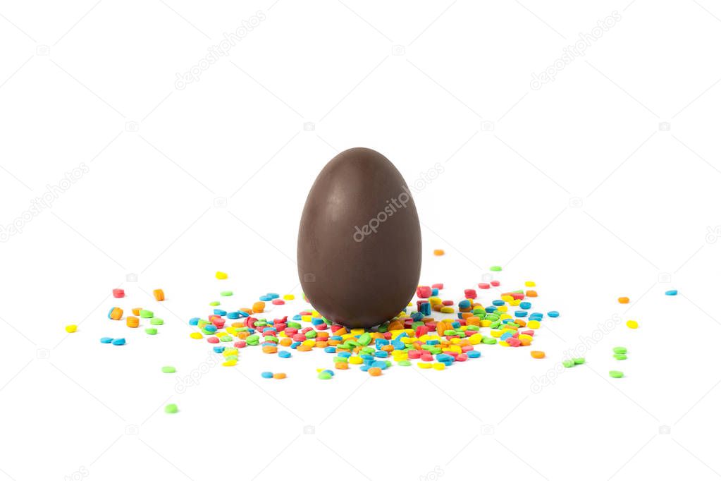 Whole Chocolate Easter Egg and multicolored sweets on a white background. Easter celebration concept