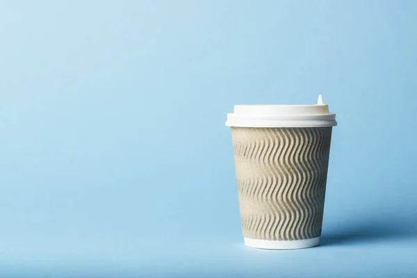 Paper cup with a plastic lid on a blue background. Hot drink concept, tea or coffee, takeaway
