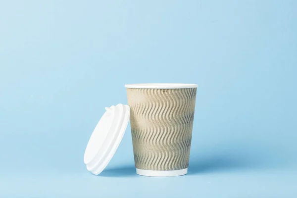 Paper cup with a plastic lid on a blue background. Hot drink concept, tea or coffee, takeaway