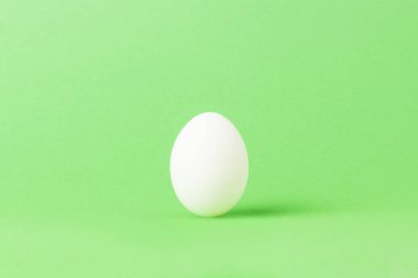 Yeşil bir arka plan üzerinde beyaz tavuk yumurta. Minimalizm. Yan görünüm
