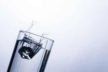 Beyaz bir arka plan üzerine bir buz küpü cam suda bir sıçrama. Susuzluğunu ve içecekler sıcak havalarda soğutma kavramı. Su dengesi ve günlük su tüketim