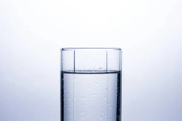 A glass of clean refreshing water on a white background. The concept of quenching thirst and cooling drinks in hot weather. Water balance and daily water consumption