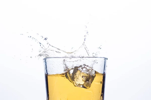 Splash of whiskey from ice cubes on a white background. Concept of alcoholic drinks with ice, whiskey or brandy, apple juice and cooling drinks