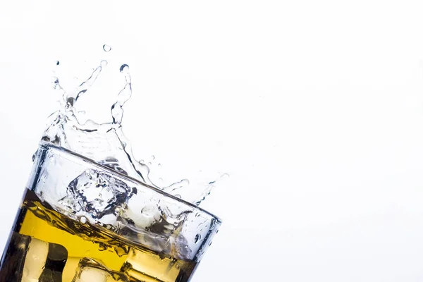 Splash of whiskey from ice cubes on a white background. Concept of alcoholic drinks with ice, whiskey or brandy, apple juice and cooling drinks