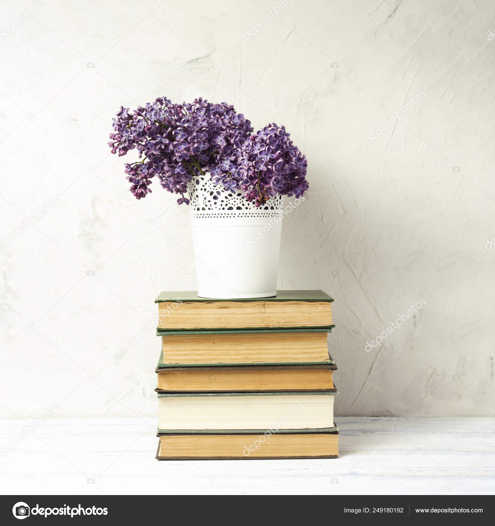 Lilac In A White Decorative Bucket On A Pile Of Books On A White