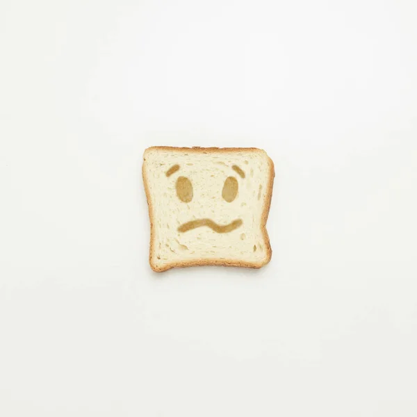 Кусок тоста с грустной улыбкой на белом фоне . — стоковое фото