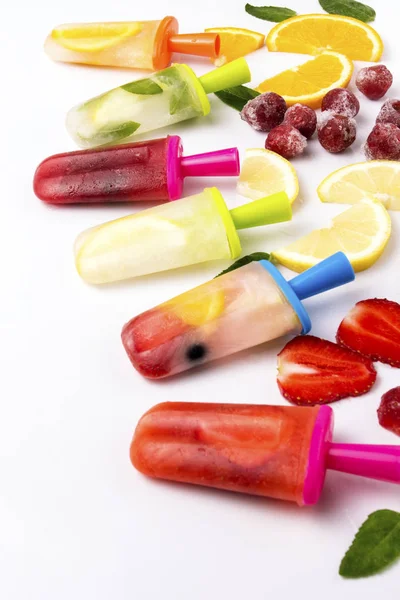 Multicolored bright fruit popsicle with strawberry, cherry, lemon, orange, lemon and mint and slices fresh fruit on a light white background — Stock Photo, Image