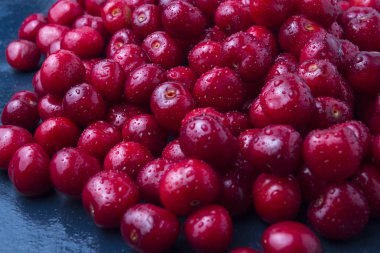 Karanlık bir bl üzerinde su ve çiğ damlaları ile taze çekilmiş kiraz