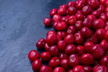 Karanlık bir bl üzerinde su ve çiğ damlaları ile taze çekilmiş kiraz