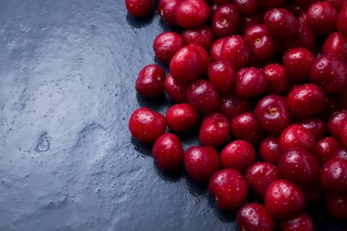 Karanlık bir bl üzerinde su ve çiğ damlaları ile taze çekilmiş kiraz