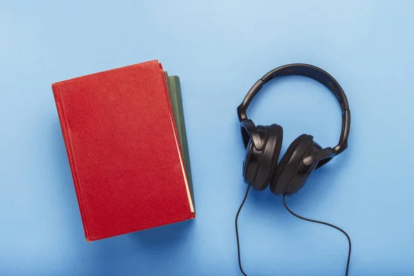 Boeken en zwarte koptelefoon op een blauwe achtergrond. Concept van audi — Stockfoto