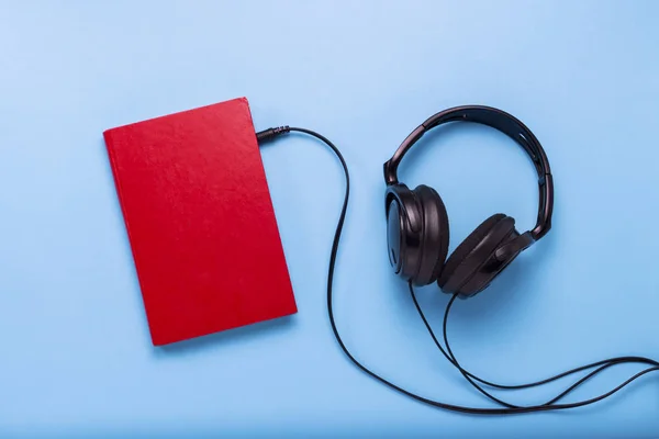 Boeken met een rode en zwarte hoofdtelefoon op een blauwe achtergrond. — Stockfoto