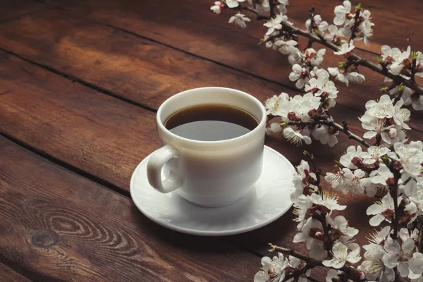 Sakura ágak, virágok és egy fehér csésze fekete kávé — Stock Fotó
