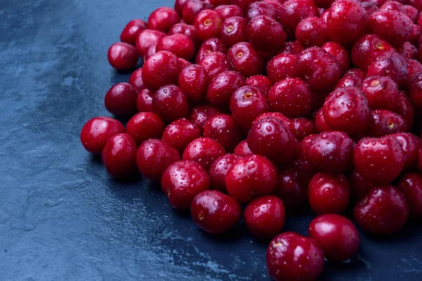 Karanlık bir bl üzerinde su ve çiğ damlaları ile taze çekilmiş kiraz