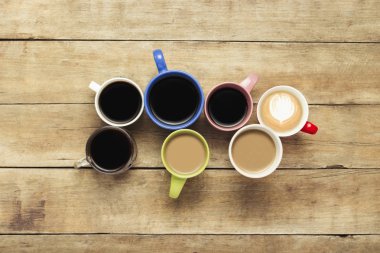 Bir sürü kahve ve kahve içecekler ahşap arka plan üzerinde renkli bardak. Kavram kahvaltı kahve, kahve arkadaş grubu. Düz yatıyordu, en iyi görünümü