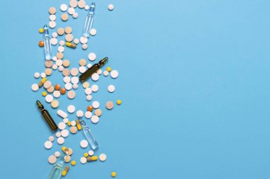 Farklı renkler ve ampul ile mavi bir arka plan üzerinde tıp hapları. İlaç endüstrisi, tıp, tedavi ve kurtarma hastalıktan sonra kavramı. Düz yatıyordu, en iyi görünümü