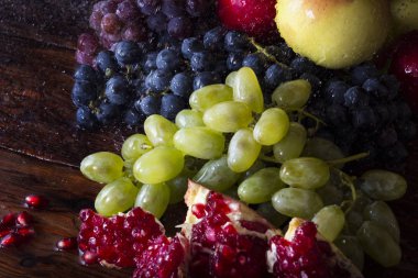 Üzüm çeşitleri, nar, nar taneleri, elma suyu bir ahşap zemin üzerine su sıçramalarına. Taze meyve kavramı, yeni ürün