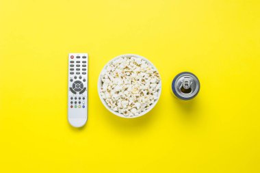 Bir kase patlamış mısır, bir Tv uzaktan, bir kutu sarı bir arka plan üzerinde bir içkiyle. Tarassut Tv, film, Tv dizisi, spor, kavramı gösterir. Düz yatıyordu, en iyi görünümü.