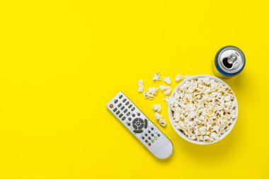 Bir kase patlamış mısır, bir Tv uzaktan, bir kutu sarı bir arka plan üzerinde bir içkiyle. Tarassut Tv, film, Tv dizisi, spor, kavramı gösterir. Düz yatıyordu, en iyi görünümü.