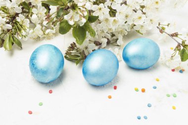 Mor mavi Paskalya yumurtaları, bahar beyaz taş zemin üzerine elma, kiraz, renkli şeker çiçekler