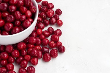 Bir beyaz taze kiraz plaka ve hafif bir taş arka plan üzerinde dağılmış