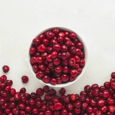 Bir beyaz taze kiraz plaka ve hafif bir taş arka plan üzerinde dağılmış. Düz yatıyordu, en iyi görünümü