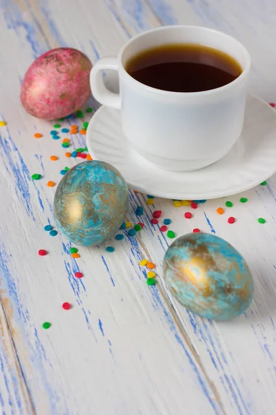 Easter Eggs and Cup of Coffee, Multicolored Sweets of Decoration on the Wooden Table. Easter concept
