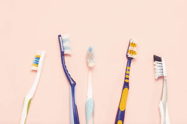 Several different used toothbrushes on a pink background. Toothbrush change concept, oral hygiene, big and friendly family, toothbrush selection. Flat lay, top view. — Stock Photo, Image