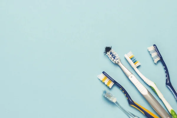 Várias escovas de dentes usadas diferentes em um fundo azul. Escova de dentes mudar conceito, higiene oral, família grande e amigável. Deitado plano, vista superior . — Fotografia de Stock