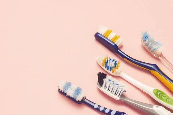 Várias escovas de dentes usadas diferentes em um fundo rosa. Conceito de mudança de escova de dentes, higiene oral, família grande e amigável, seleção de escova de dentes. Deitado plano, vista superior . — Fotografia de Stock
