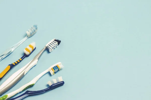 Várias escovas de dentes usadas diferentes em um fundo azul. Conceito de mudança de escova de dentes, higiene oral, família grande e amigável, seleção de escova de dentes . — Fotografia de Stock