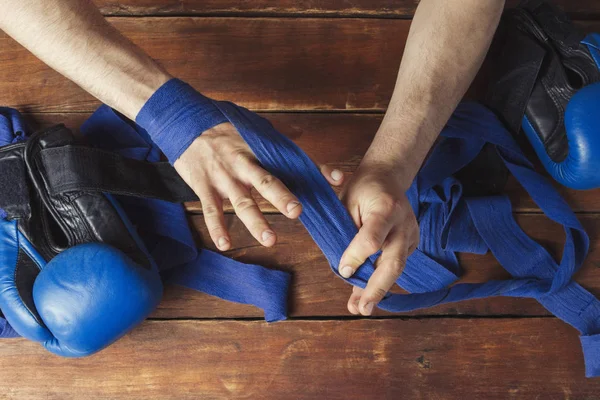 Hombre vendaje cinta de boxeo en sus manos antes de la lucha de boxeo sobre un fondo de madera. El concepto de entrenamiento para entrenamiento de boxeo o lucha. Piso tendido, vista superior —  Fotos de Stock
