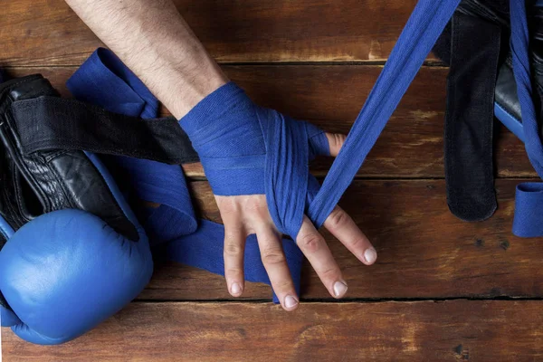 Proceso de pegar las manos masculinas antes de un combate de boxeo sobre un fondo de madera. Guantes de boxeo yacen sobre la mesa. El concepto de boxeo es aprender o luchar. Piso tendido, vista superior —  Fotos de Stock