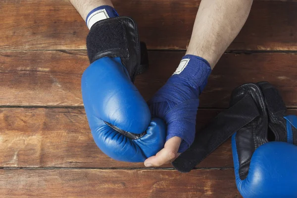 Manos de hombre en vendas de boxeo y guantes de boxeo sobre un fondo de madera. Preparación conceptual para entrenamiento de boxeo o combate. Piso tendido, vista superior —  Fotos de Stock
