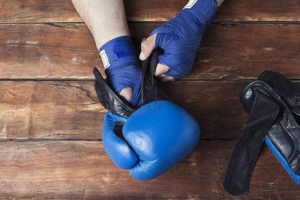 Men\'s hands in boxing bandages and boxing gloves on a wooden background. Concept preparation for boxing training or combat. Flat lay, top view