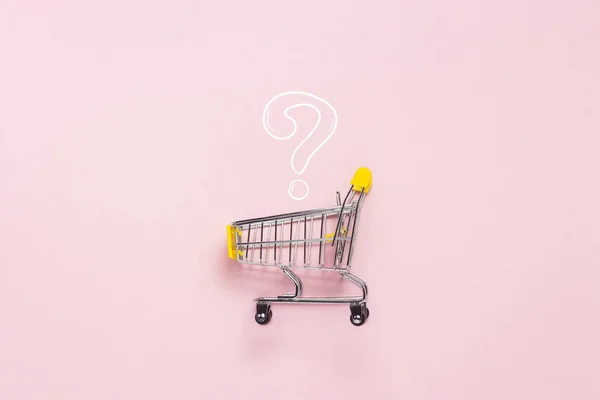 Einkaufswagen aus dem Supermarkt auf isoliertem rosa Hintergrund. Einkaufen in der Mall, einkaufen, einkaufen, eine große Auswahl. Fragezeichen. flache Lage, Draufsicht. — Stockfoto