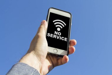 Adam elinden bir telefon tutarak ve mavi gökyüzüne karşı bir sinyal vayf bulmaya çalışır. Telefon ekranında, sinyal simgesi