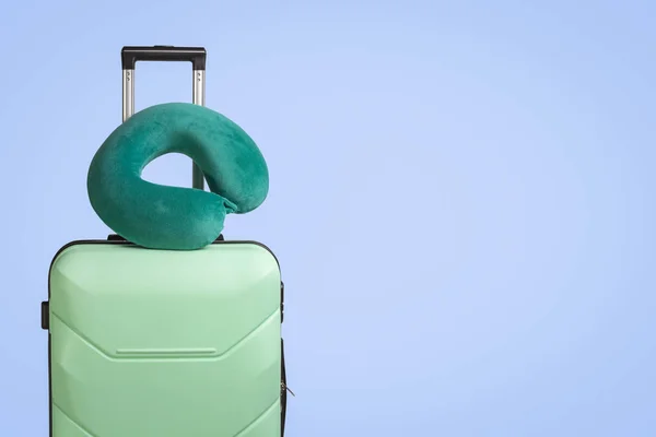 Plastikową walizkę i podróż poduszki na niebieskim tle. Koncepcja podróży, podróże służbowe, wycieczki do odwiedź przyjaciół i krewnych — Zdjęcie stockowe